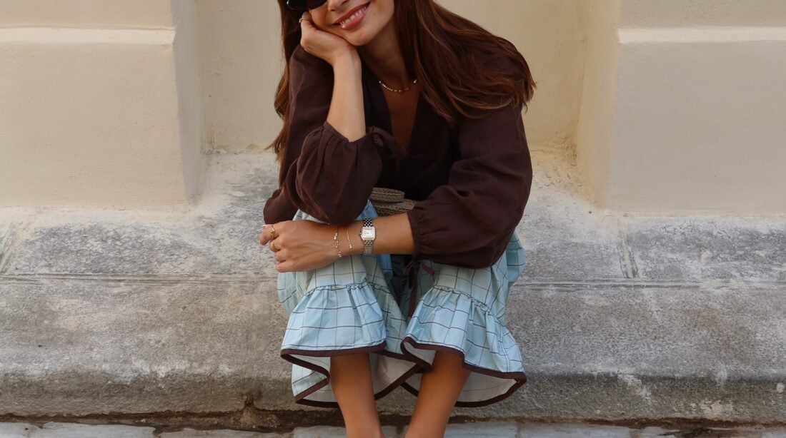 Look de trabalho com blusa bata marrom e calça quadriculada azul em mulher branca