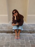Look de trabalho com blusa bata marrom e calça quadriculada azul em mulher branca