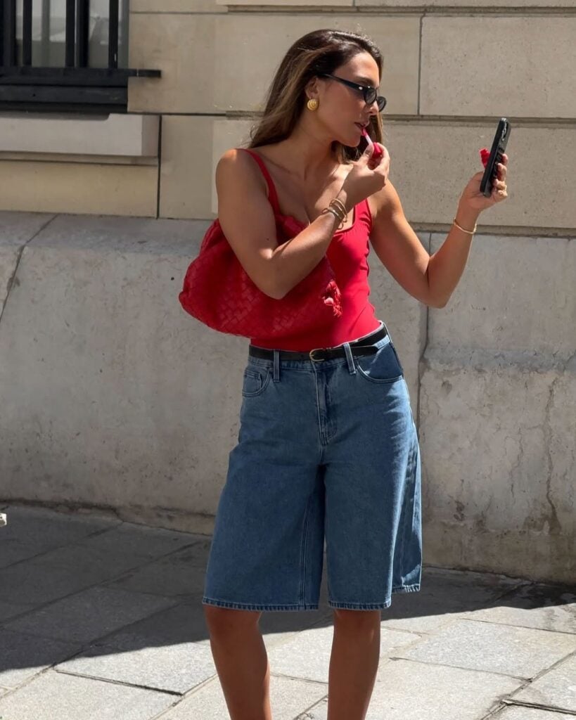 Look de trabalho com bermuda jeans e blusa vermelho com decote quadrado em mulher branca e magra