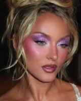 Zara Larsson com cabelo loiro preso e maquiagem em tons de lilás