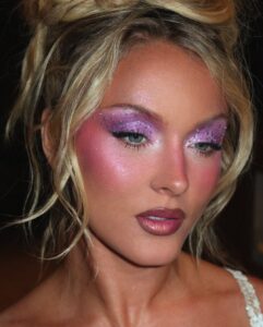 Zara Larsson com cabelo loiro preso e maquiagem em tons de lilás