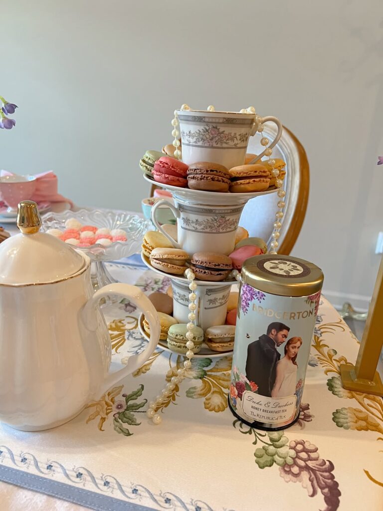 Mesa com toalha com frutas, bandeja de três andares com macarons