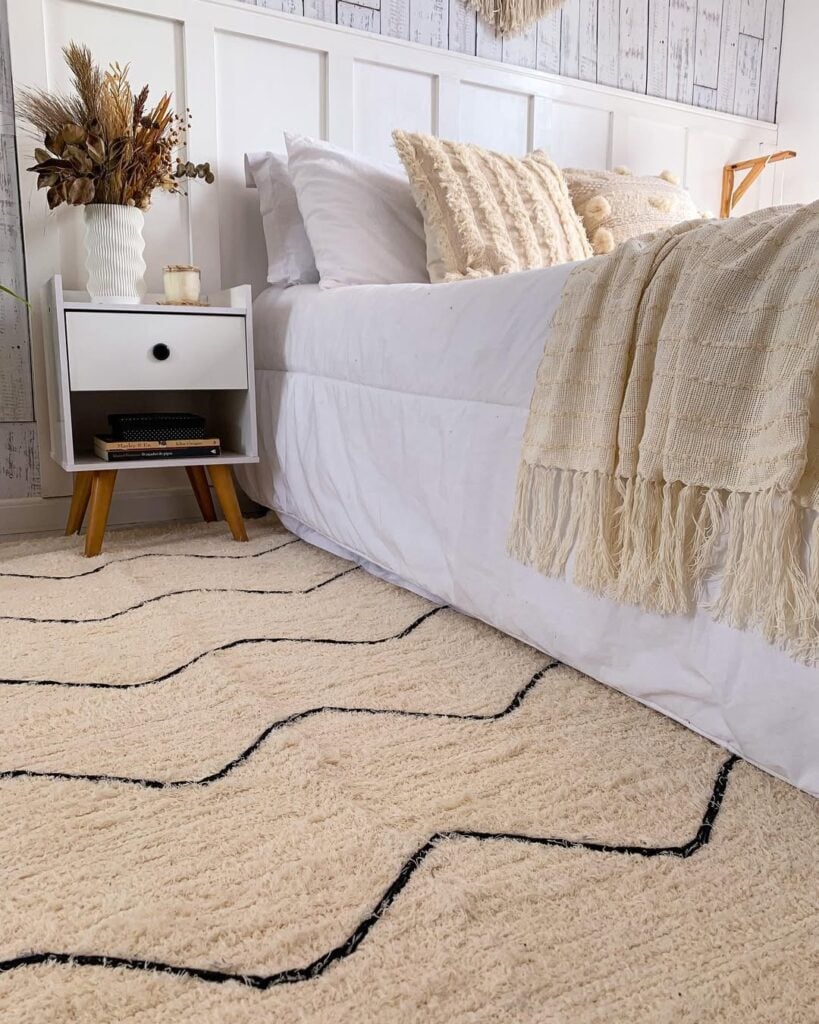 Quarto com tapete bege e detalhes pretos e mesa de cabeceira branca