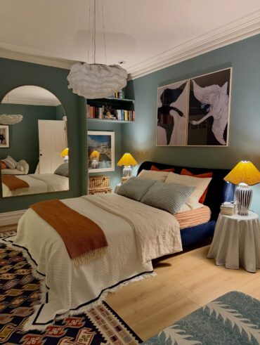 Quarto de casal com cama, quadro, lustre, tapete, mesa de cabeceira e abajur