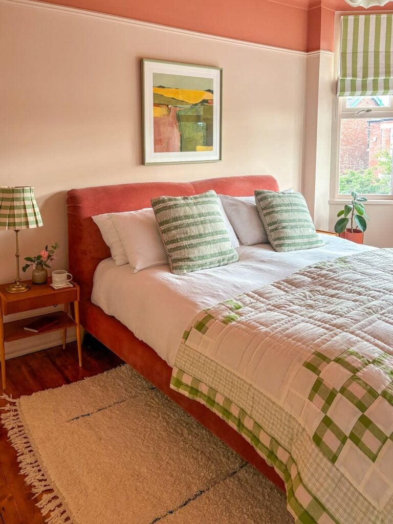 Quarto de casal com cama, quadro, tapete, mesa de cabeceira e abajur