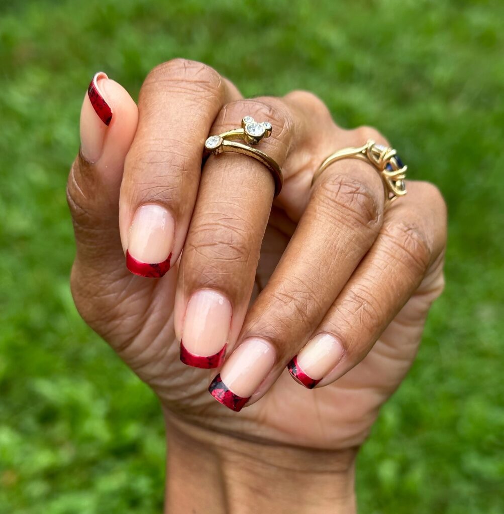 Unhas com francesinha vermelha em mão de pele negra