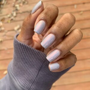 Unhas cintilantes em tom de lilás em mão de pele negra