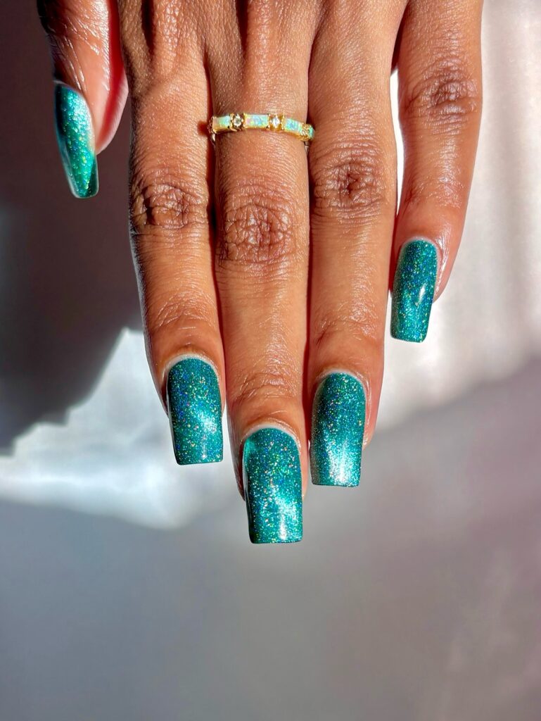 Unhas com esmalte azul com glitter em mão de pele negra