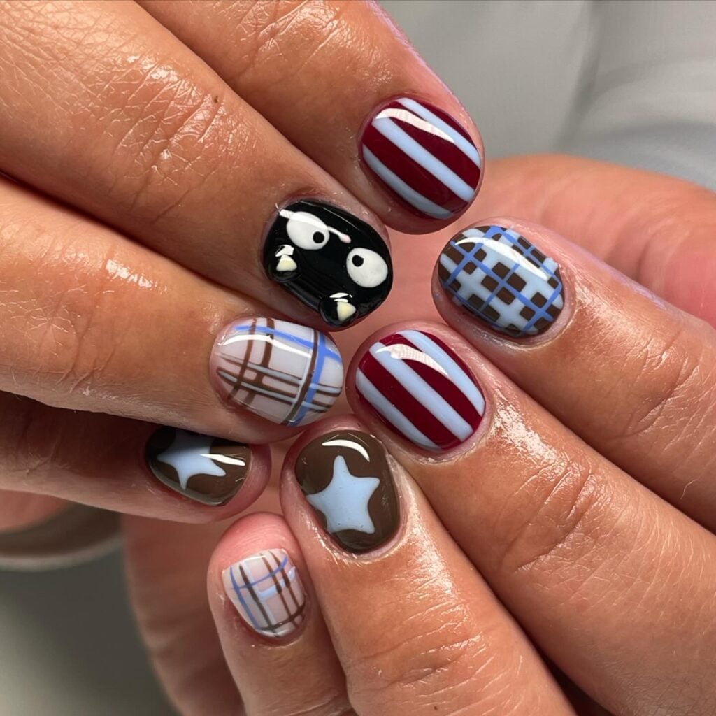 Unha curta com técnica de nail art maximalista com listras, estrelas e xadrez em mão de pele negra
