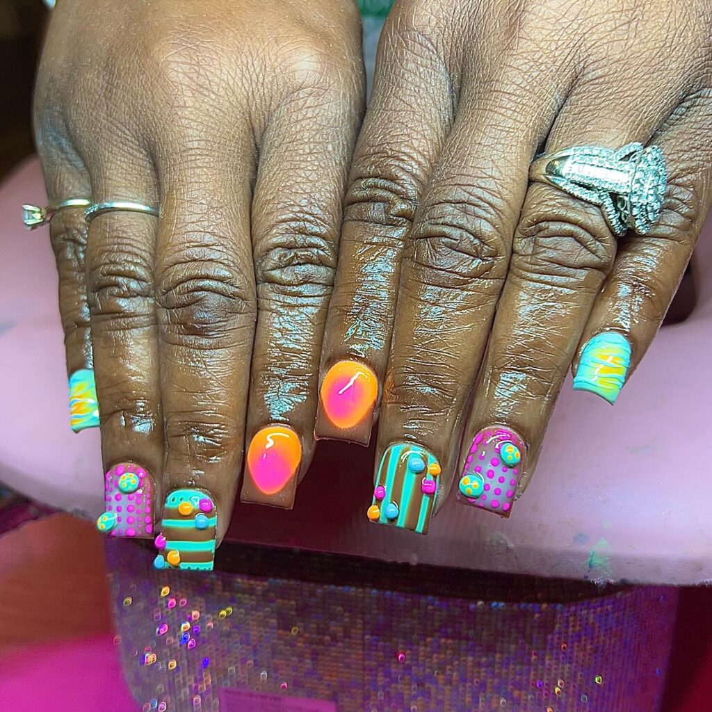 Unha curta com técnica de nail art maximalista com listras e gel 3D em mão de pele negra