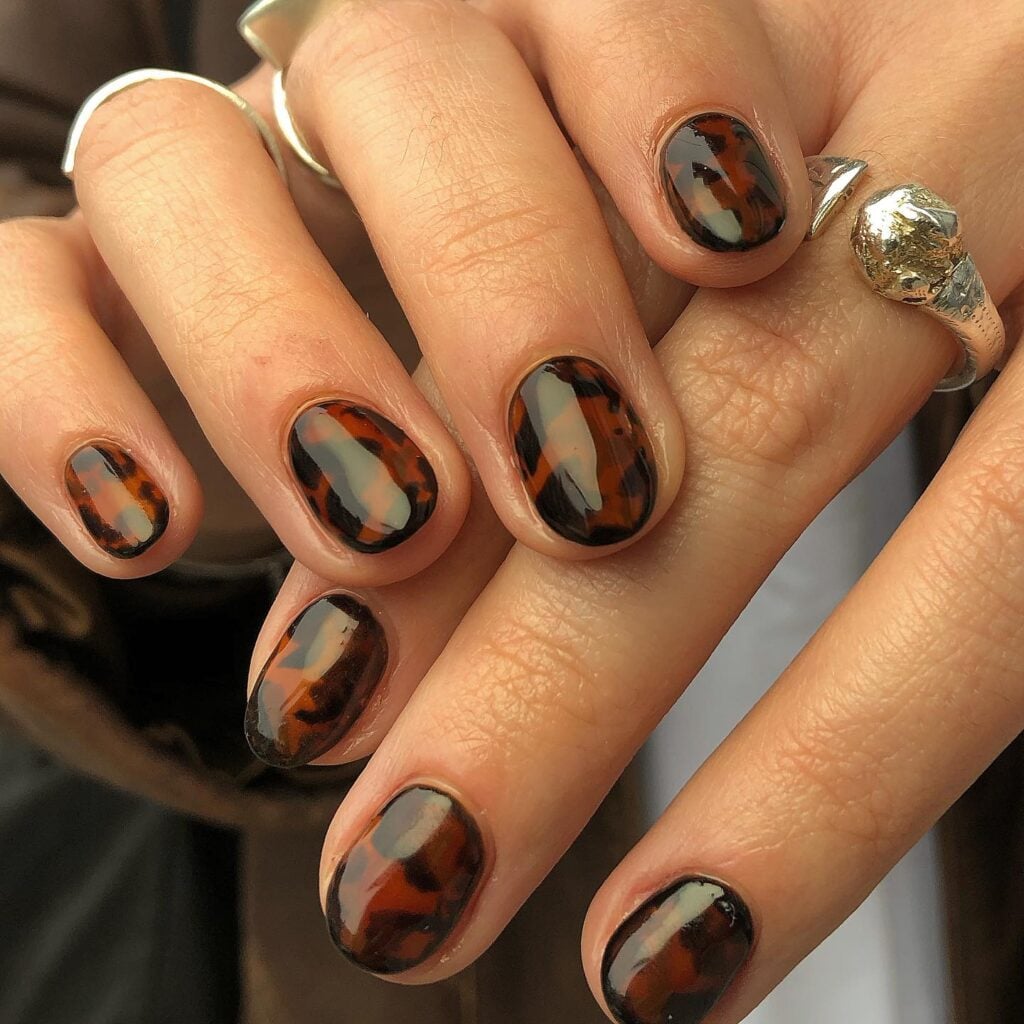 Unhas de casco de tartaruga com nail art com esmalte preto e marrom
