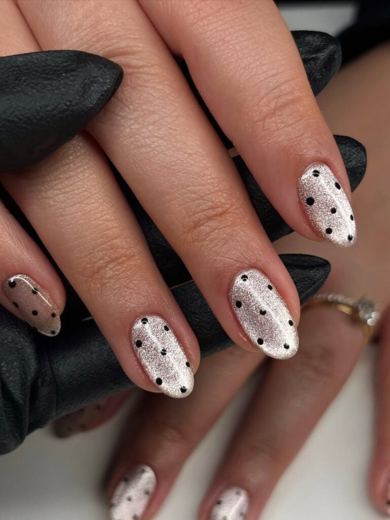 Mãos de pele clara, com unha amendoada cat eye com poá