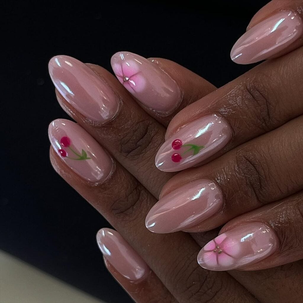 Mãos de pele preta, com unha amendoada rosa-claro com cerejas e flores