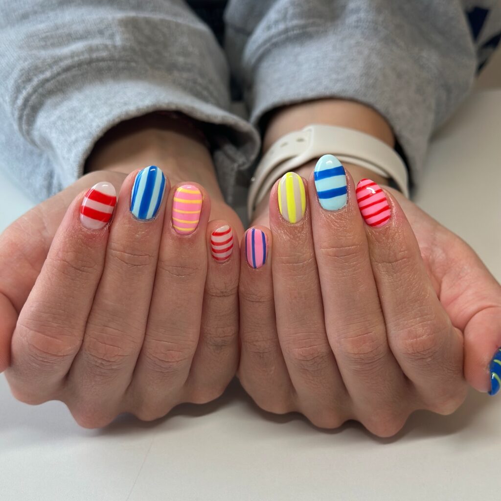 Unhas listradas em mão de pele branca estão entre as tendências de beleza