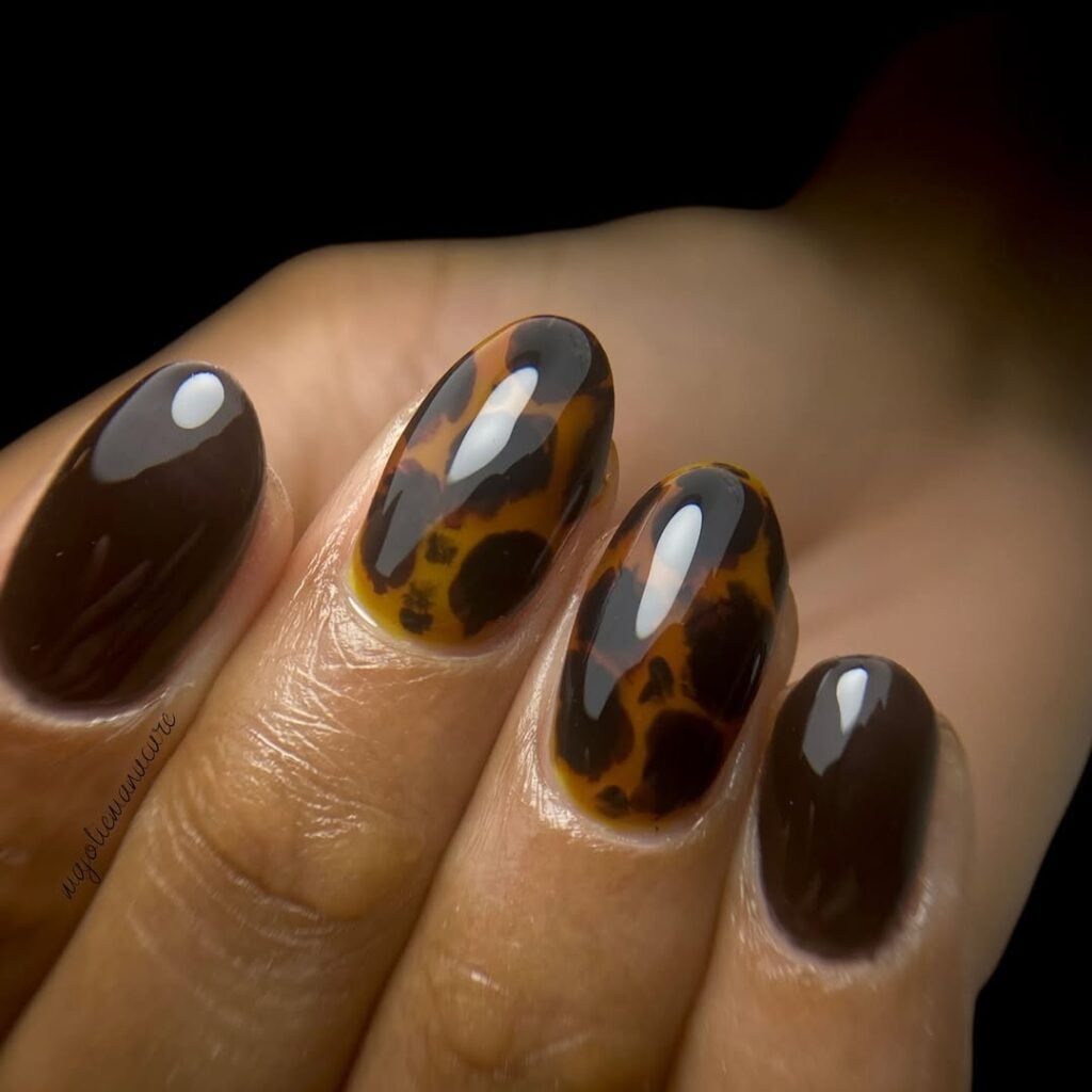 Unhas de tartaruga em mão de pele negra e estampa de animal print
