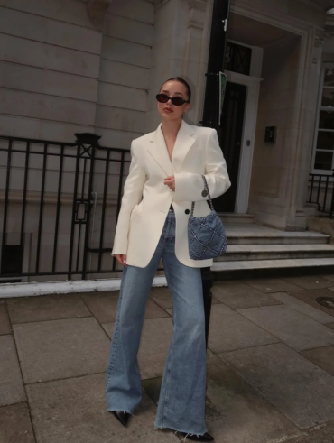Mulher jovem, magra e de pele clara com blazer claro e calça jeans