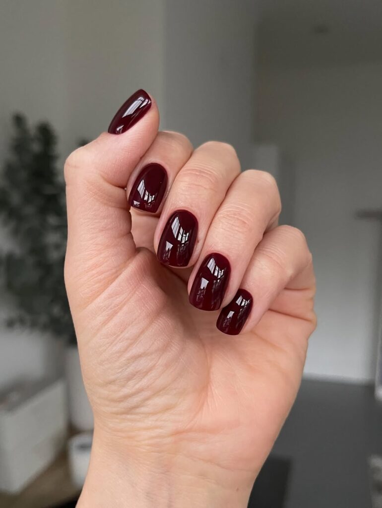 Mão de pele clara, com unha curta e quadrada burgundy