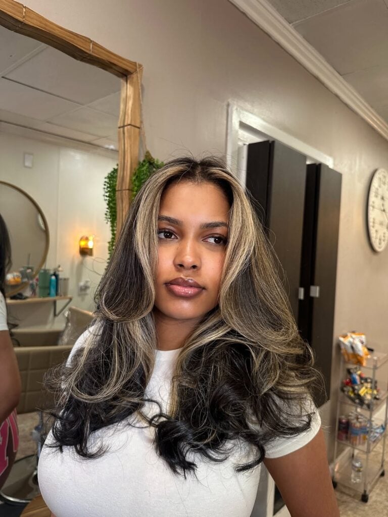 Mulher de pele preta, com blusa branca e cabelo loiro acinzentado