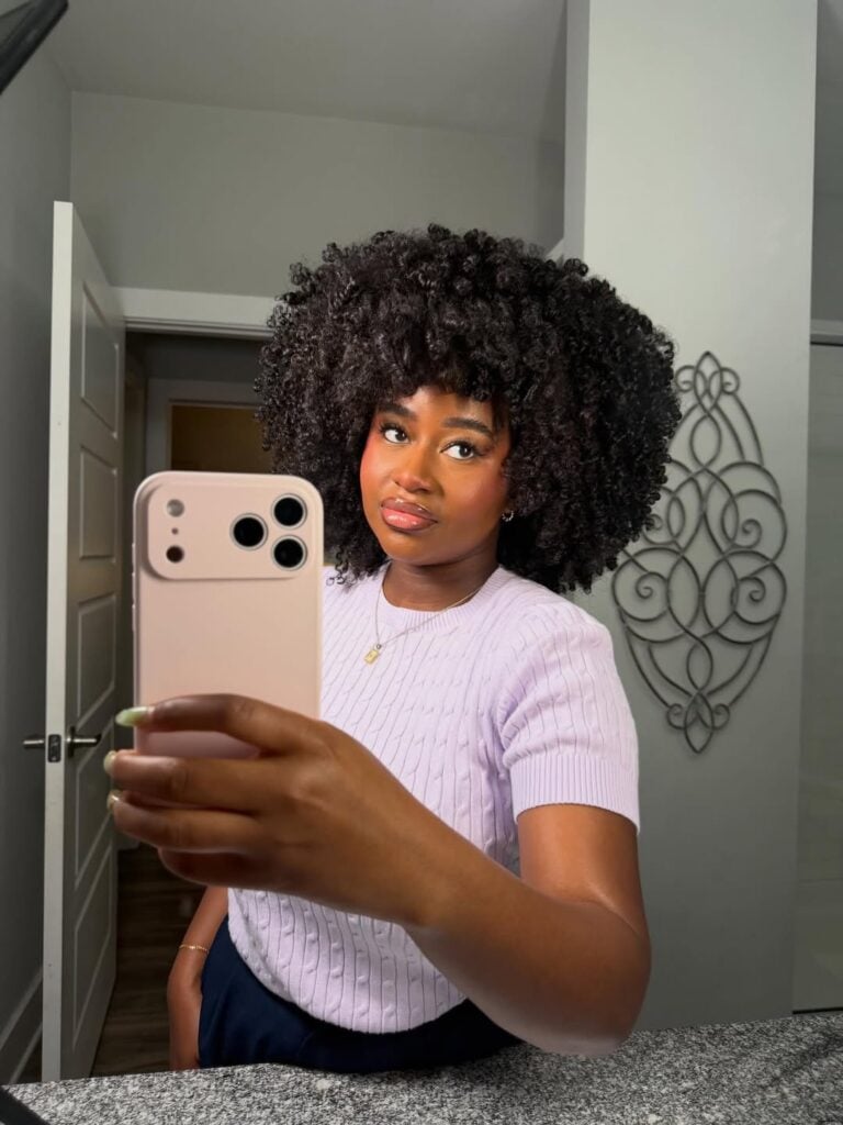 Mulher de pele preta, com blusa branca e cabelo black power