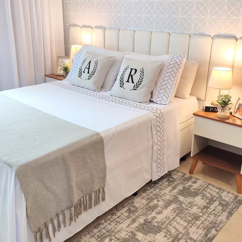Cama posta branca com lençol, manta e almofadas