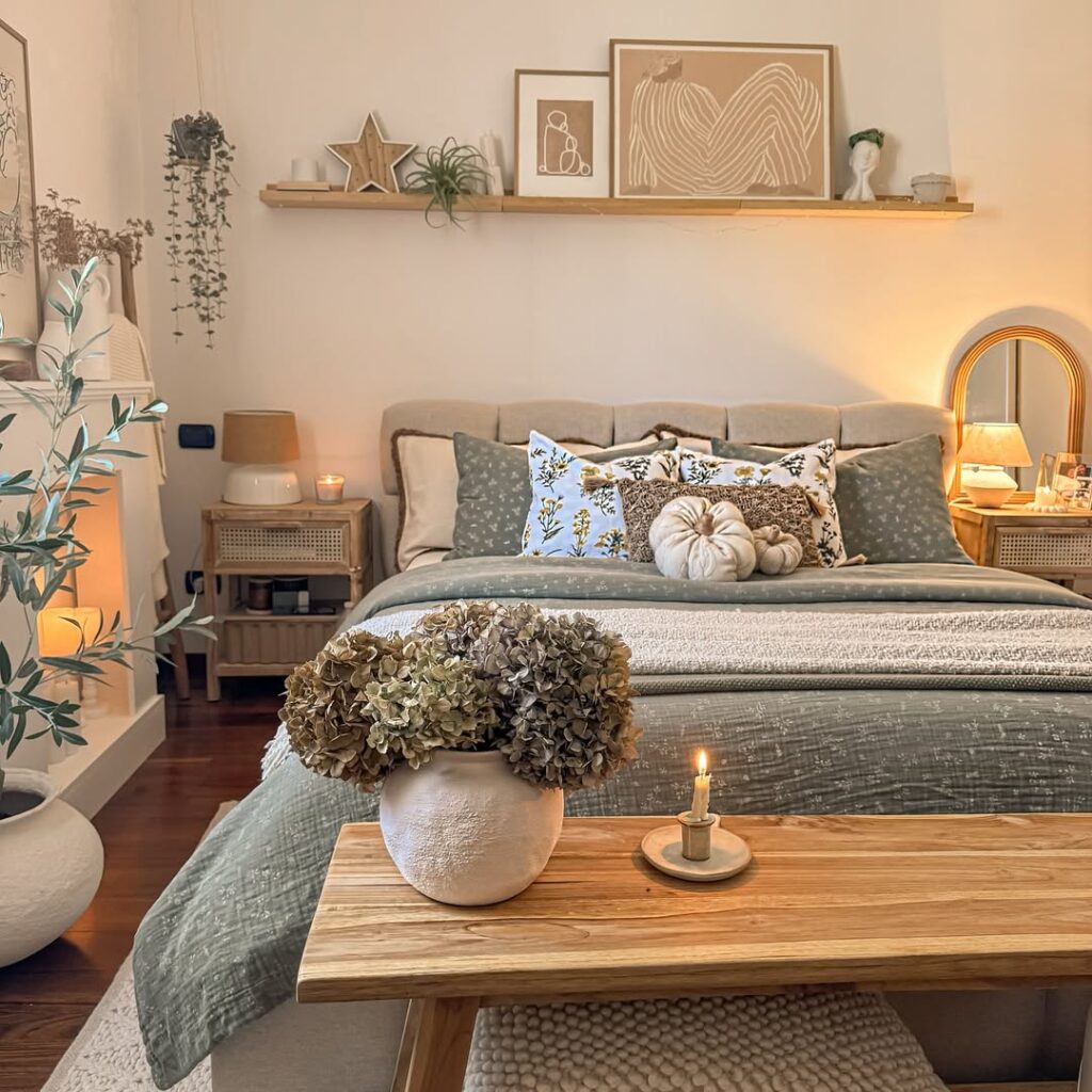 Quarto em tons de bege e cinza, cama com almofadas, manta, plantas e iluminação quente
