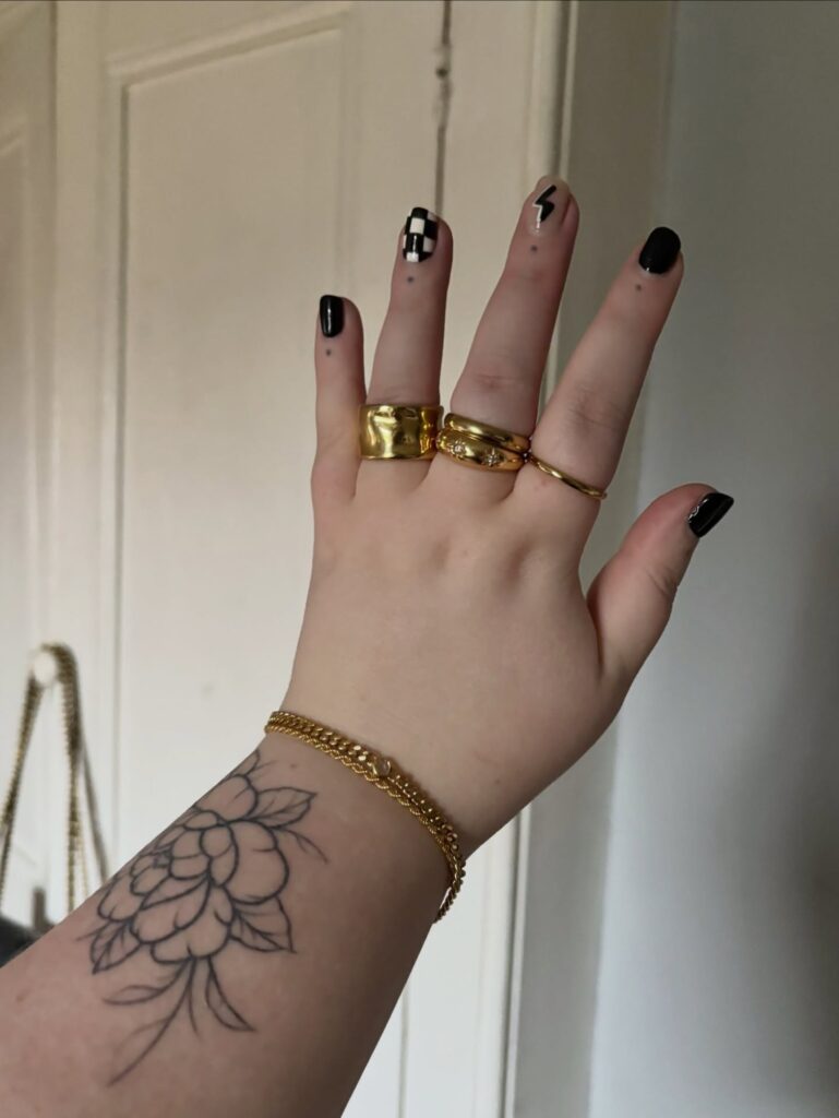 Mão de pele branca com unha preta com raio e checkerboard nails ou unhas de tabuleiro de xadrez com efeito quadriculado