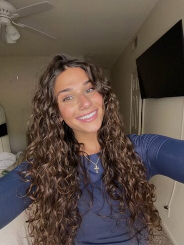 Mulher de pele clara, com blusa azul e cabelo castanho cacheado