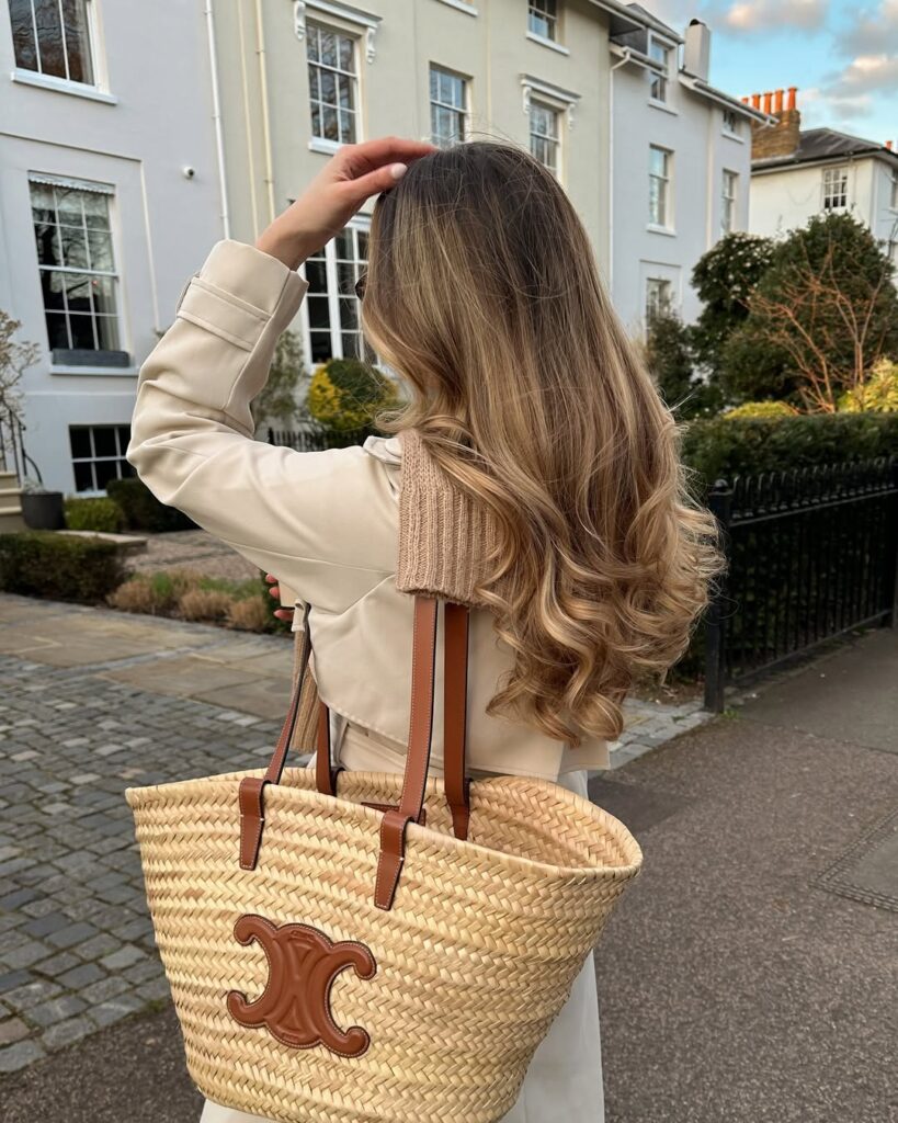 Mulher de pele clara, com casaco bege e cabelo com mechas loiras
