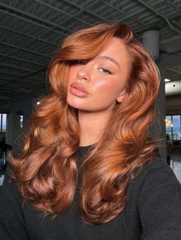 Mulher de pele clara, com blusa preta e cabelo cobre