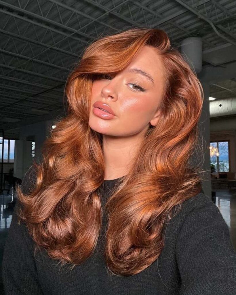Mulher de pele clara, com blusa preta e cabelo cobre