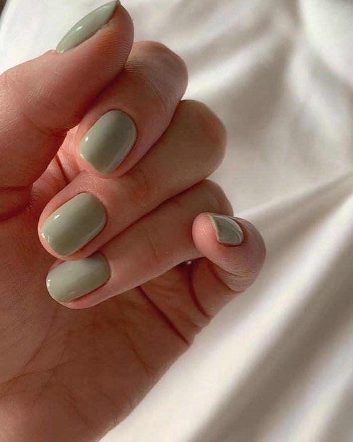Mão de pele clara, com unha curta verde-sálvia