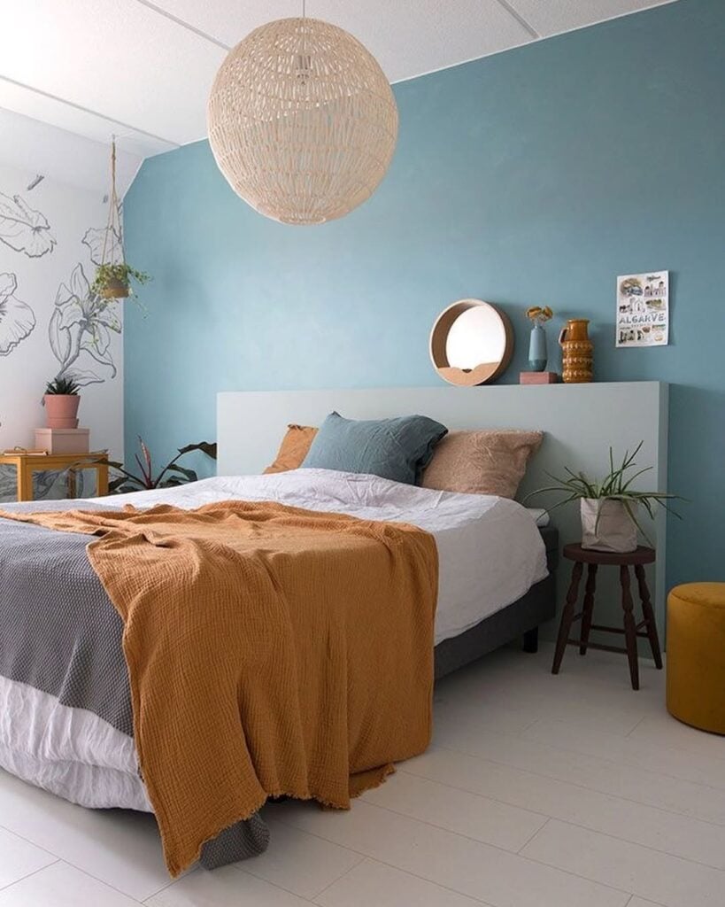 Quarto com parede azul, luminária de fibras naturais e parede com papel de parede branco