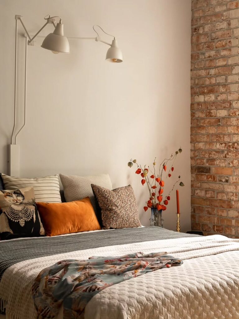 Cama com cores e texturas de outono e luminária na parede