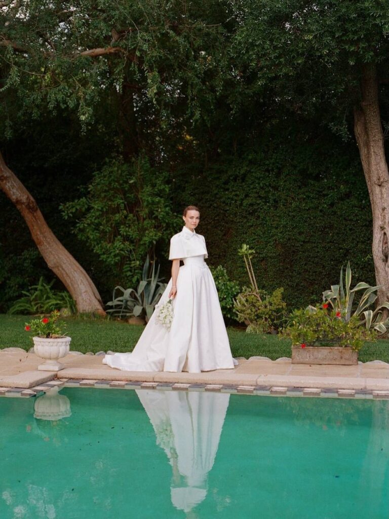 Mulher de pele clara, com vestido branco com capa