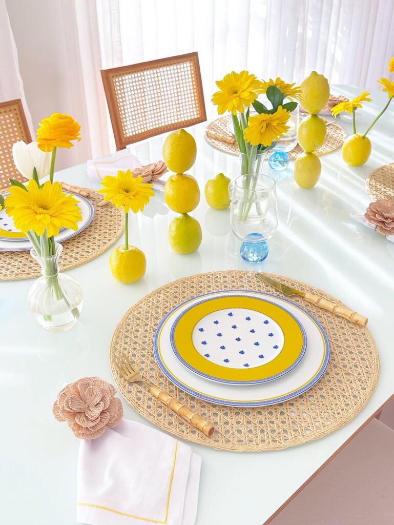 Ideia de mesa psota com sousplat de palhinha, pratos com azul, branco e amarelo e limões sicilianos empilhados na decoração