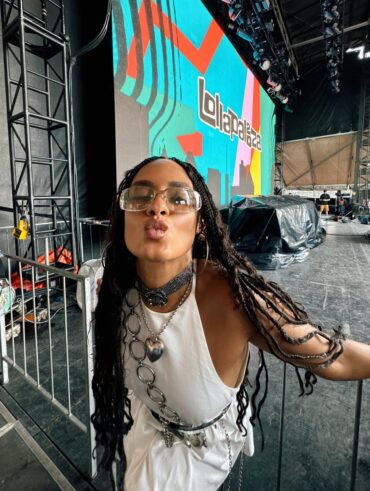 Mulher de pele preta, com look branco e cabelo trançado