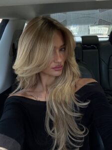 Mulher de pele clara, com blusa preta e cabelo longo loiro
