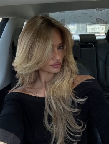 Mulher de pele clara, com blusa preta e cabelo longo loiro