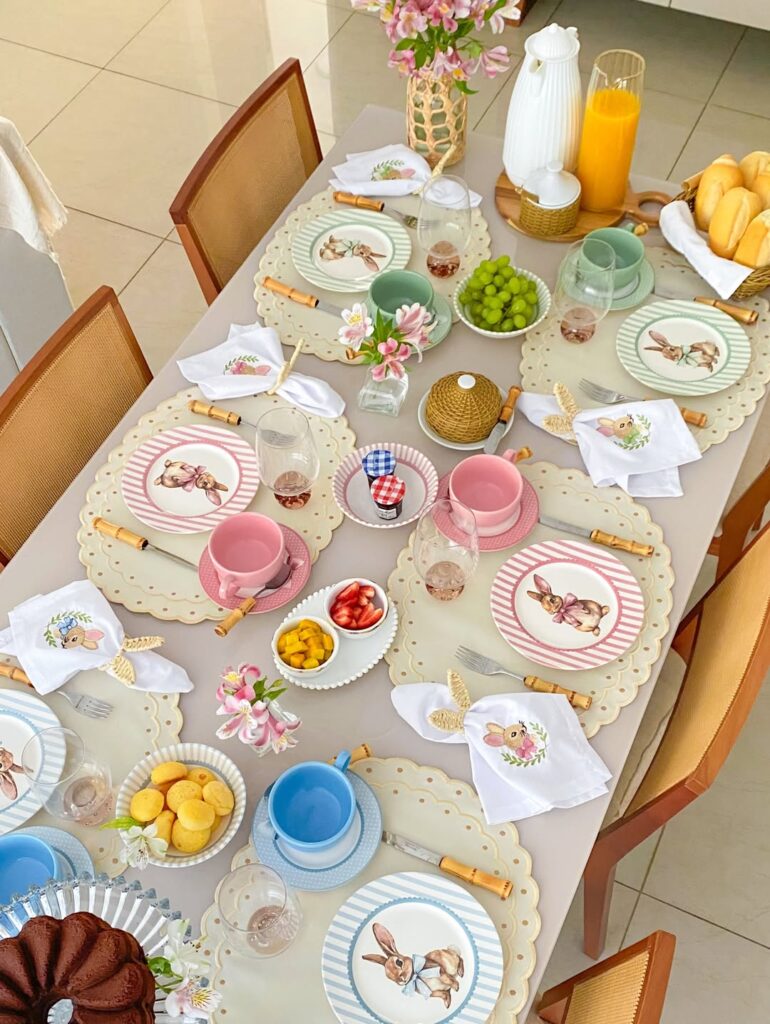 Mesa posta de páscoa com jogos americanos, pratinhos listrados com coelhos e xícaras coloridas