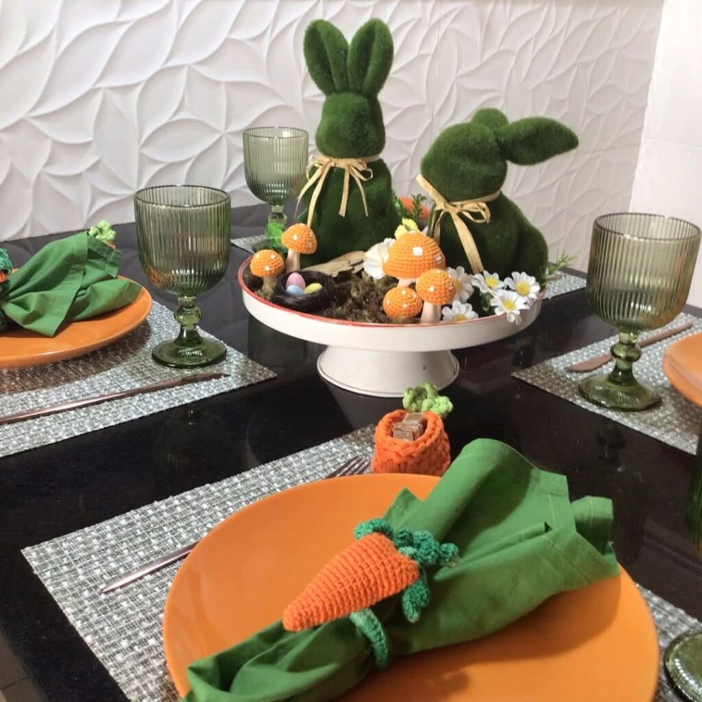 Mesa de páscoa colorida e divertida com pratos laranja e guardanapos verdes com cenouras de crochê