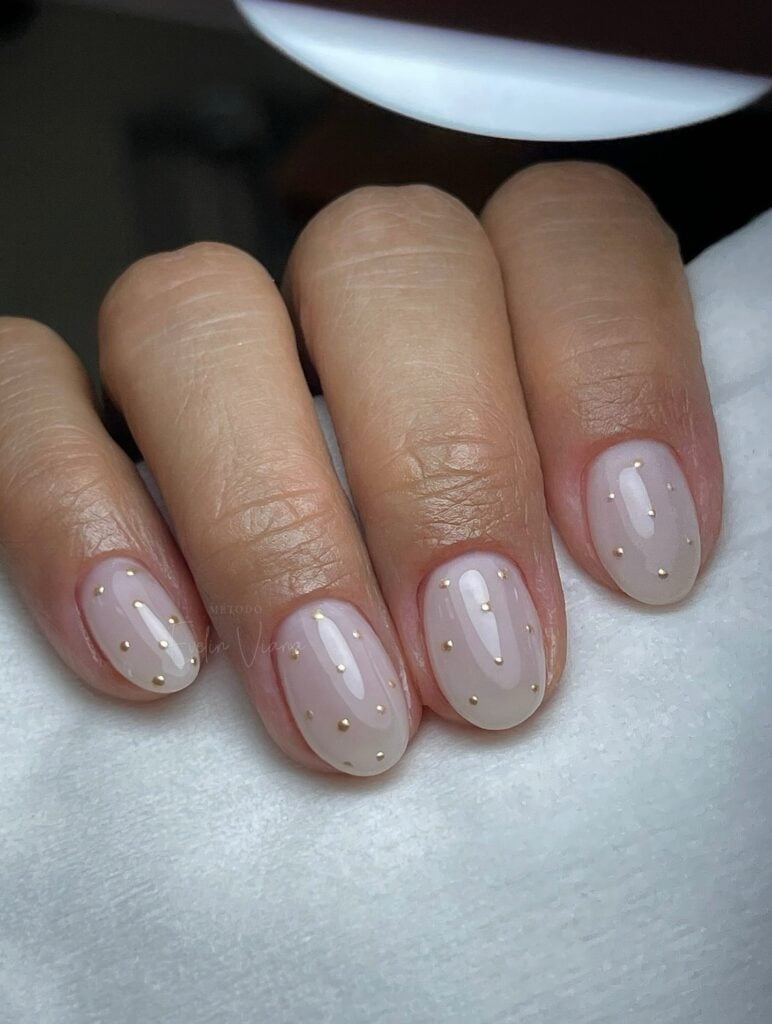 Unha de gel em mão de pele branca com nail art com poá polka dot nails