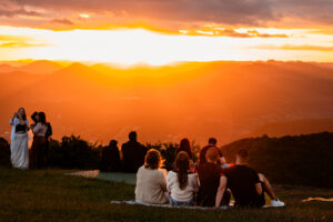 Pessoas sentadas na grama diante do pôr do sol em Nova Petrópolis
