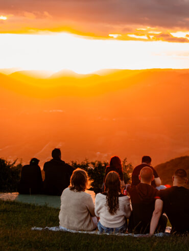 Pessoas sentadas na grama diante do pôr do sol em Nova Petrópolis