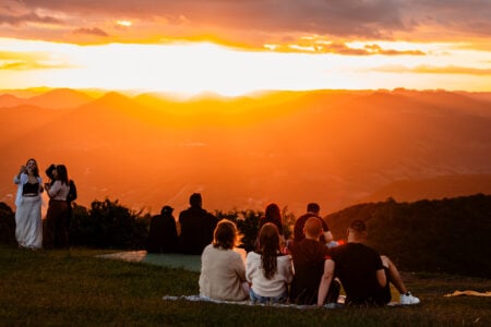 Pessoas sentadas na grama diante do pôr do sol em Nova Petrópolis