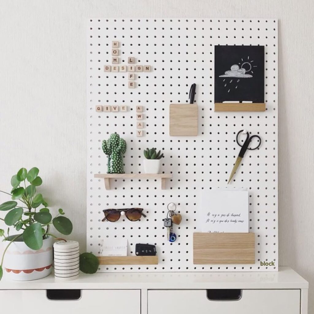 Pegboard branco em cima de bancada com óculos, tesoura, chaves