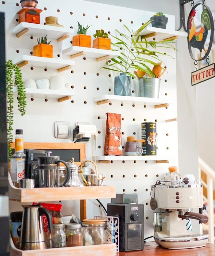 Pegboard branco na cozinha com prateleiras, plantinhas e itens de cozinha