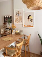Inspiração de quadros na cozinha com imagens na mesma paleta de cores, moldura branca e mesa e cadeiras de madeira