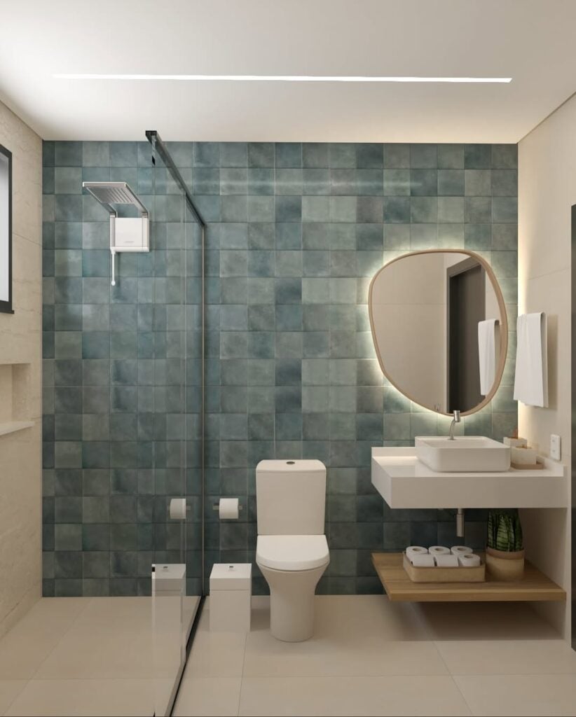 Banheiro com parede azul, loucas brancas e espelho orgânico com led