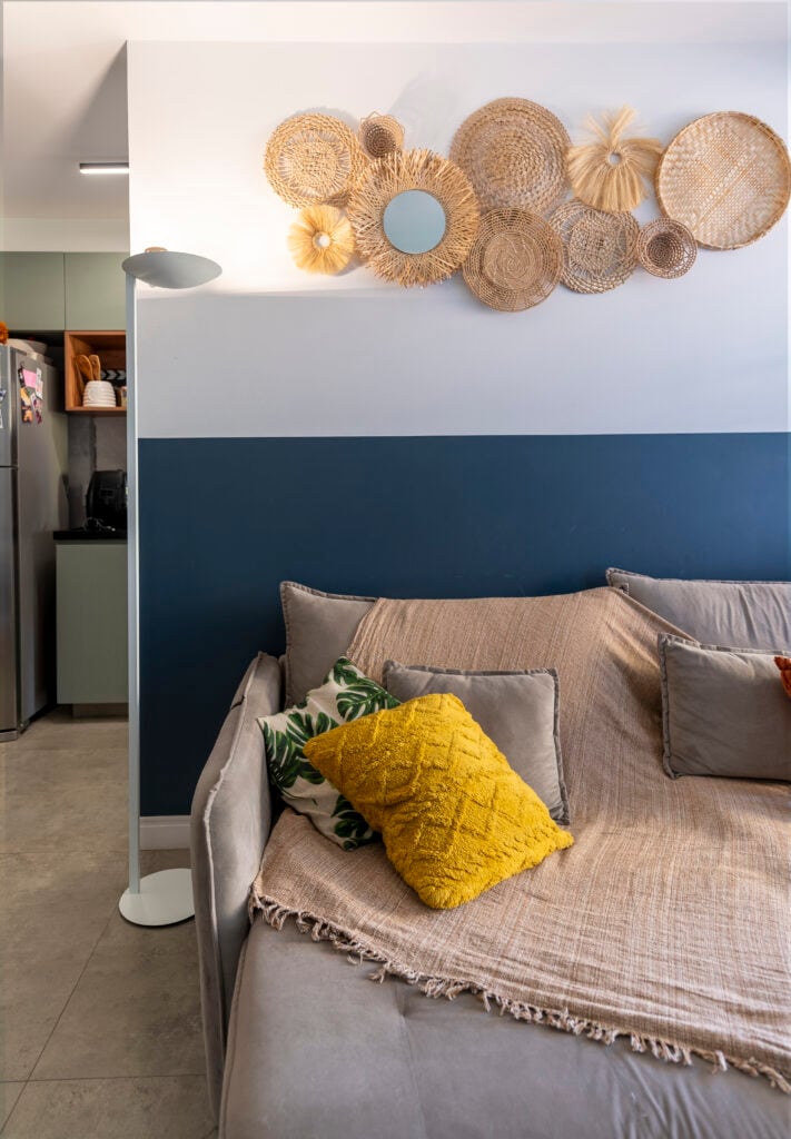 Sala com meia parede azul e meia branca com itens decorativos em palha