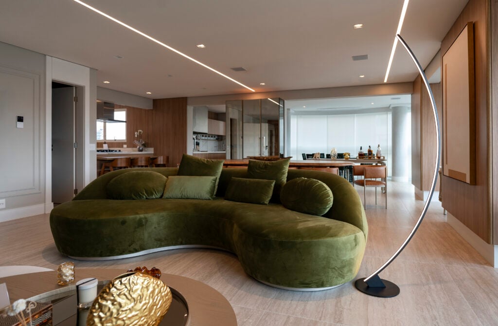 Sala com sofá de formas curvas verde em veludo